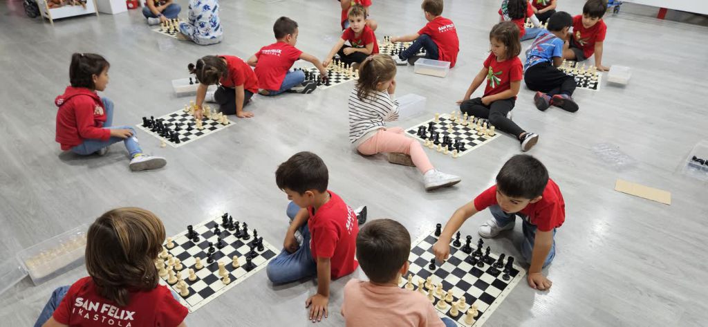 Varios txikis de San Felix juegan al ajedrez sentados en el suelo del aula