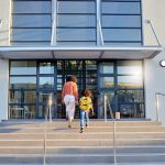 Una madre y su hija subiendo las escaleras de entrada del colegio